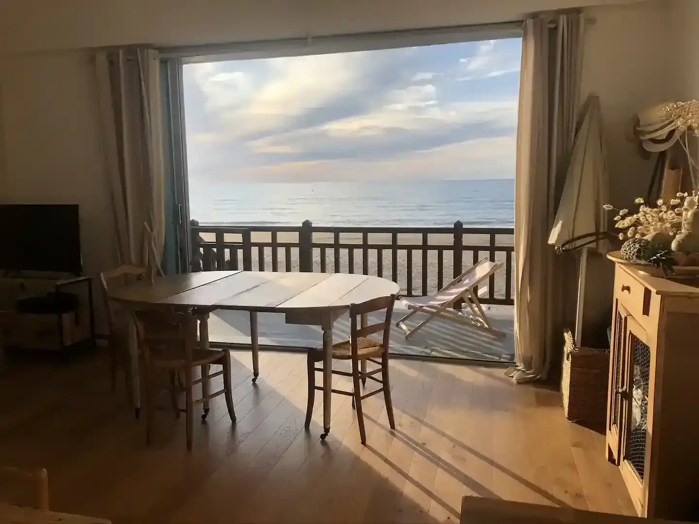 Salon-vue-mer-coucher-soleil-villa-sauvagine Salon ouvert avec grande baie vitrée sur la plage au coucher du soleil à la Villa Sauvagine