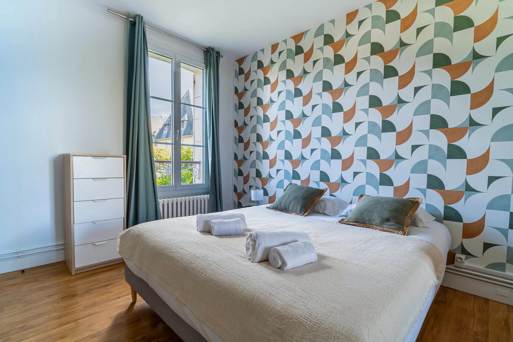 Chambre avec papier peint graphique – Evasion Normande Chambre design avec papier peint géométrique et lit double dans la maison Evasion Normande.