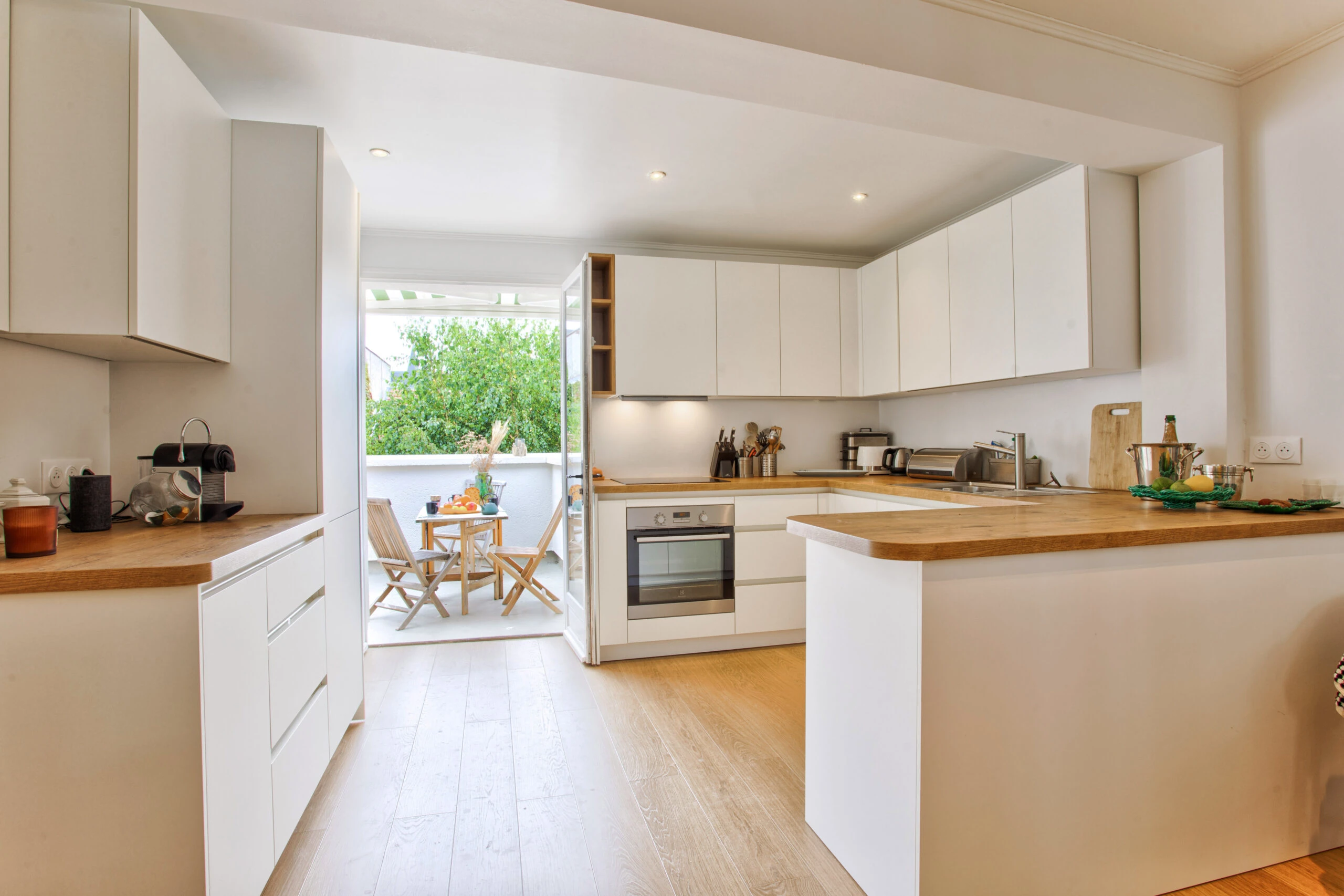 Cuisine équipée avec terrasse en arrière-plan – maison Laguna Cuisine moderne avec plan de travail en bois et accès direct à une terrasse extérieure – maison Laguna
