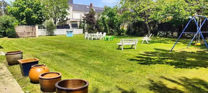 Grand jardin verdoyant – Evasion Normande Vaste jardin entretenu avec balançoire et mobilier de jardin, parfait pour des activités familiales dans la maison Evasion Normande.