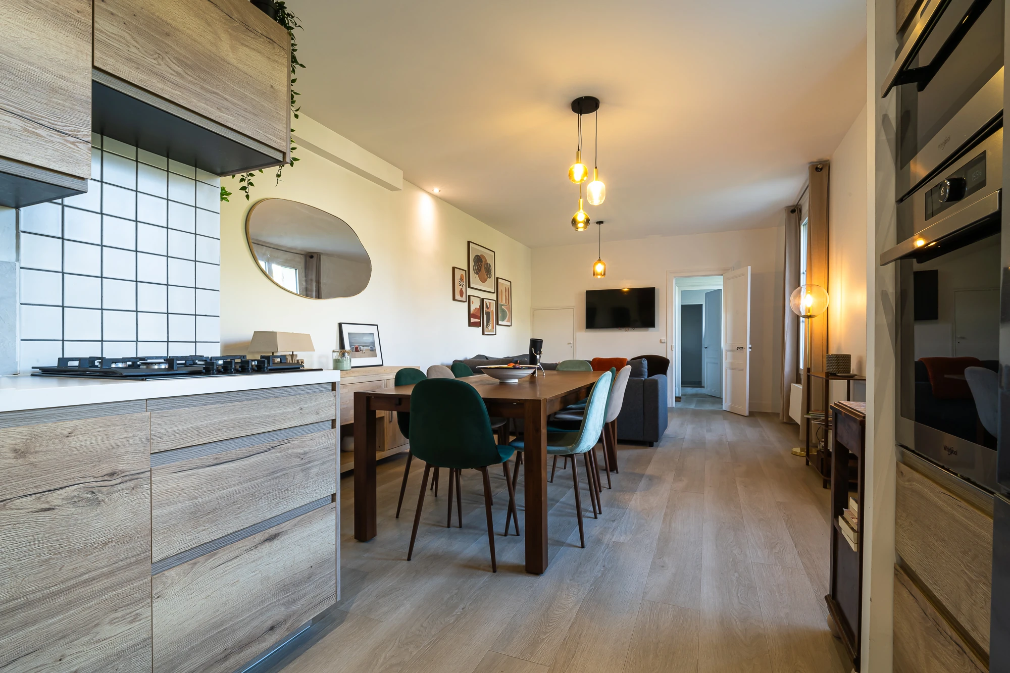 Salle à manger conviviale – Evasion Normande Salle à manger ouverte sur le salon avec table en bois et décoration lumineuse dans la maison Evasion Normande.