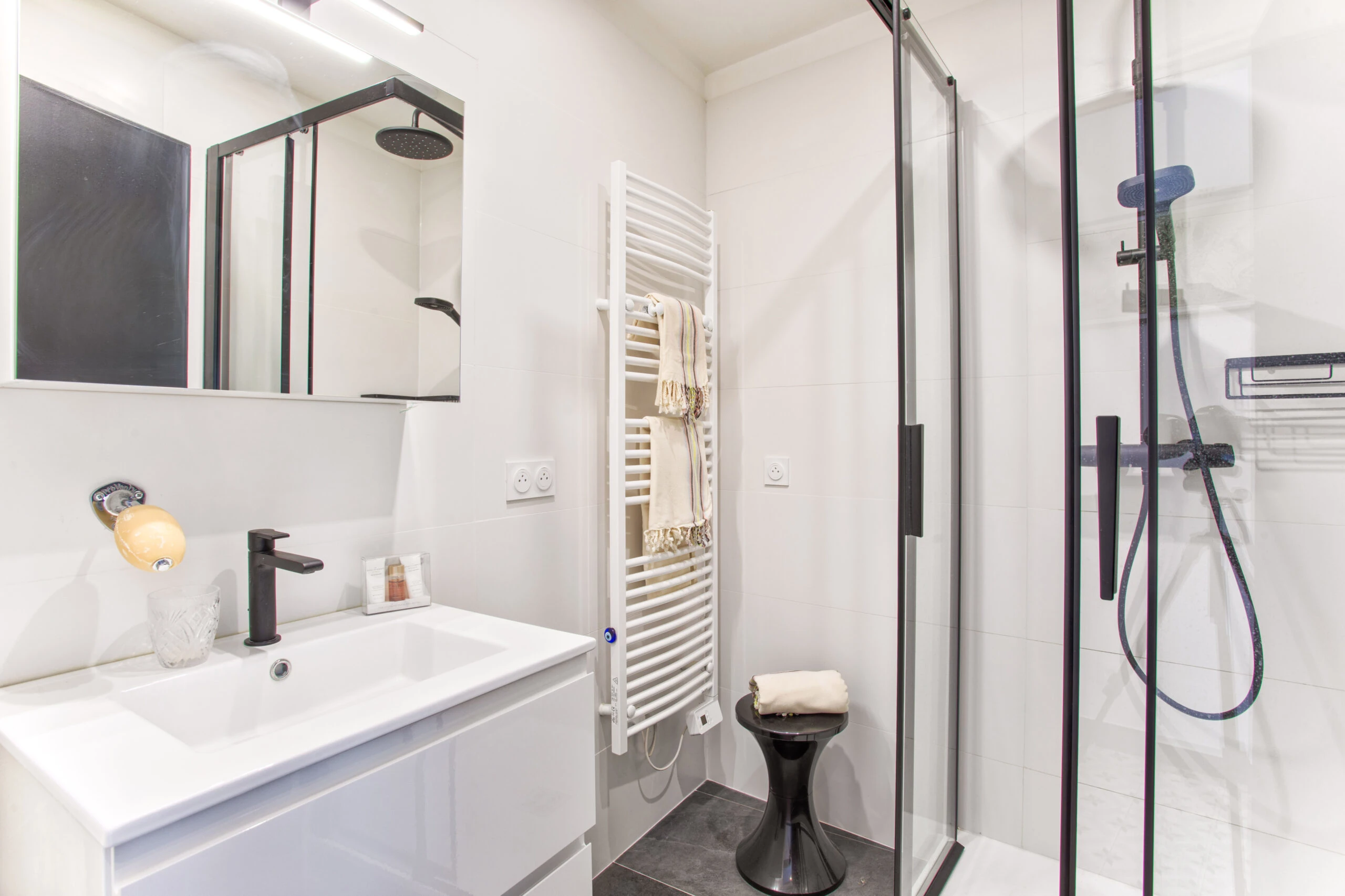 Salle d’eau moderne avec douche à l’italienne noire – maison Laguna Salle d’eau contemporaine avec douche noire, sèche-serviettes blanc et meuble vasque design – maison Laguna