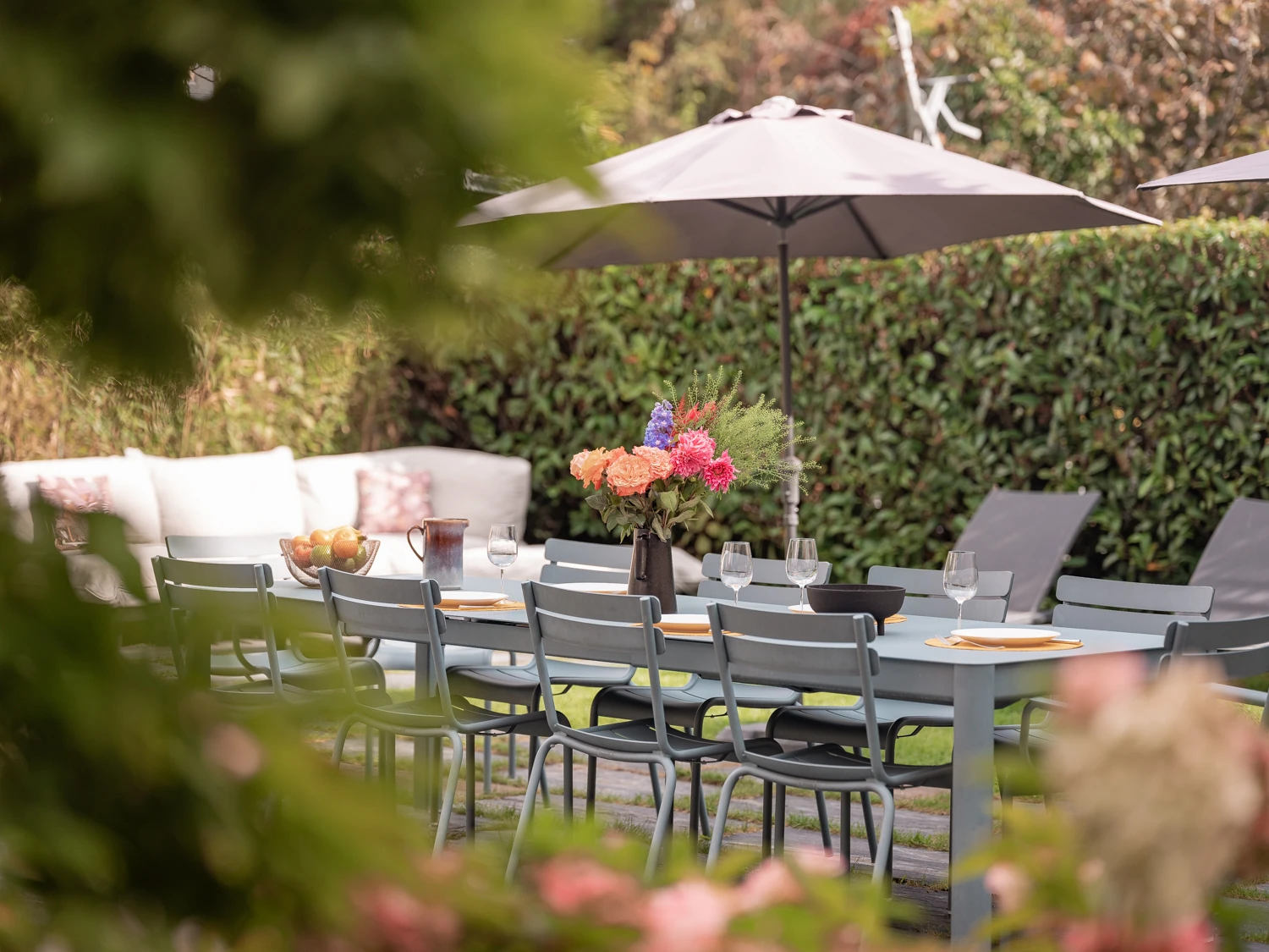 Table de jardin avec fleurs – Villa Berry Porte d'entrée bleue encadrée de plantes et détails architecturaux raffinés.