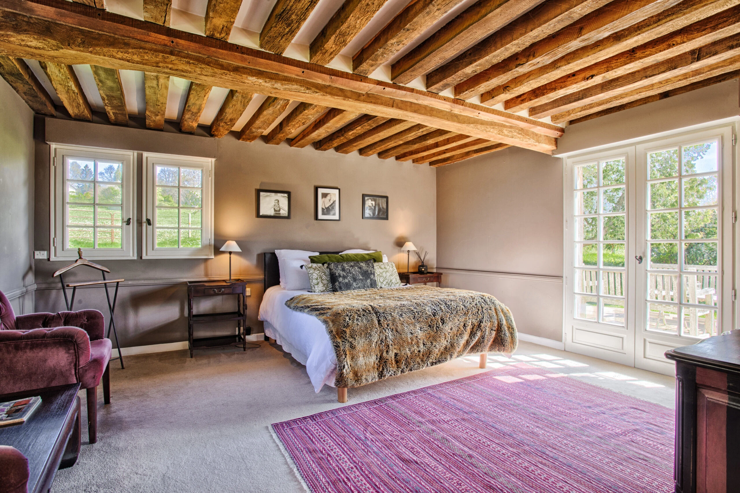 Chambre principale avec poutres au plafond apparentes – Villa Constantin Grande chambre avec lit double, plafond à poutres en bois et accès terrasse dans la Villa Constantin