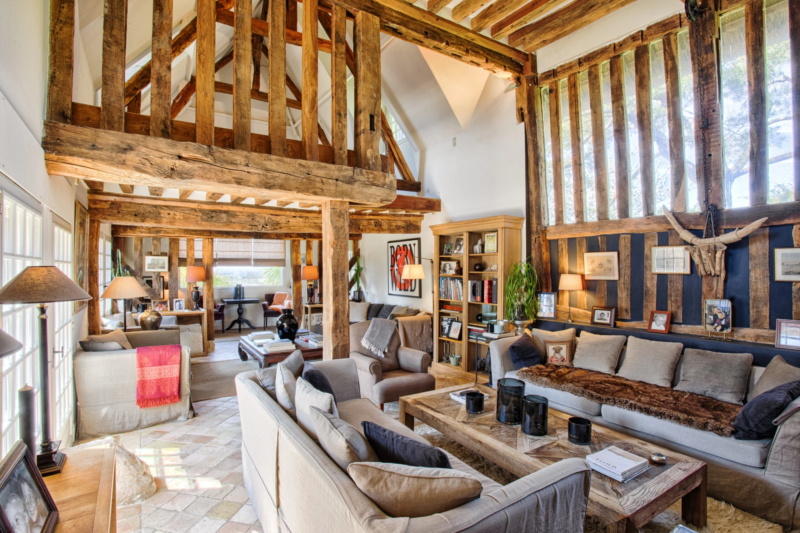 Double salon avec charpente apparente – Villa Constantin Salon spacieux avec poutres apparentes, mobilier confortable et grande luminosité dans la Villa Constantin