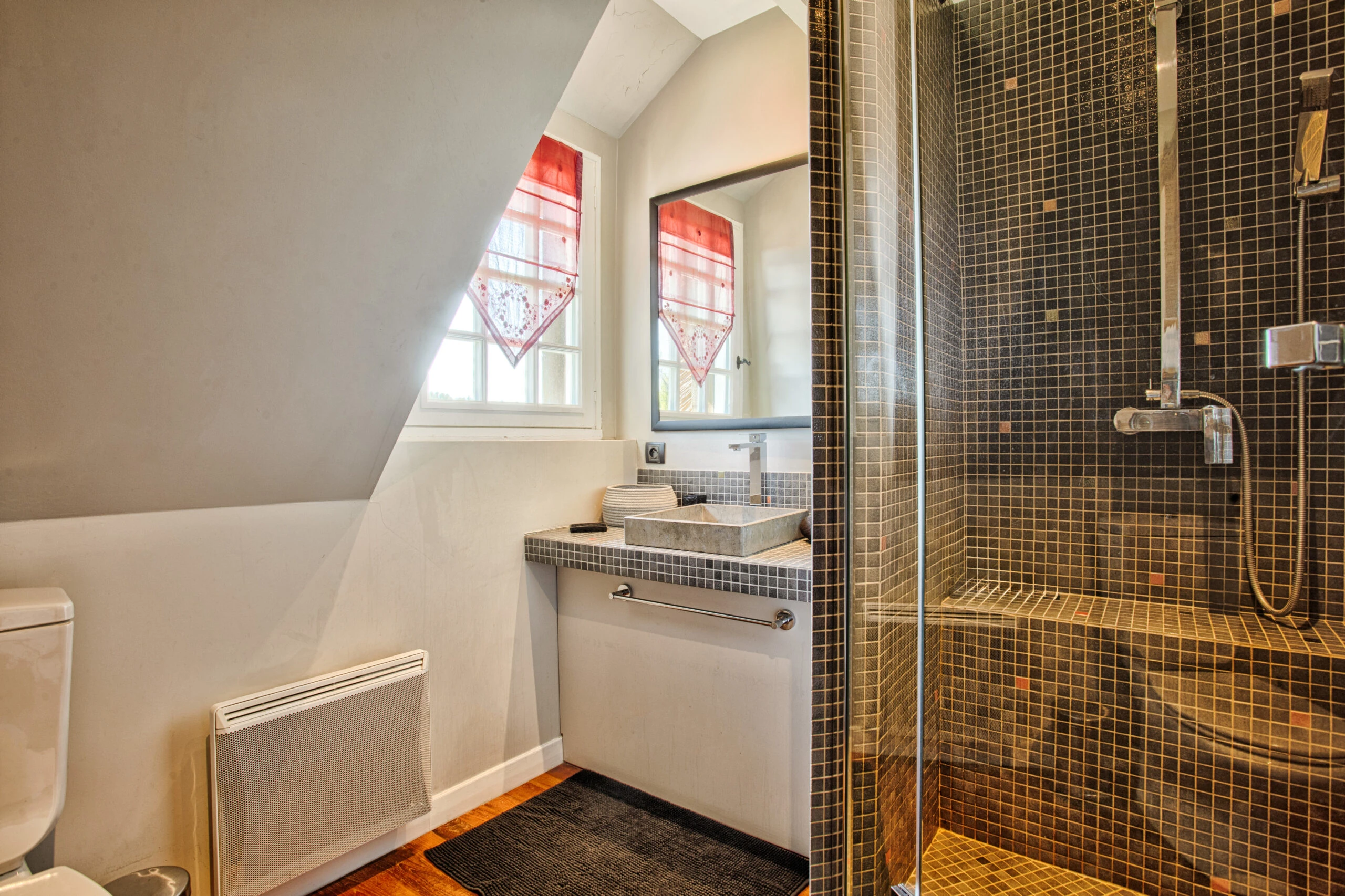 Salle de bain sous les combles avec douche moderne – Villa Constantin Salle de bain cosy sous les combles, équipée d’une douche moderne et d’une vasque design dans la Villa Constantin