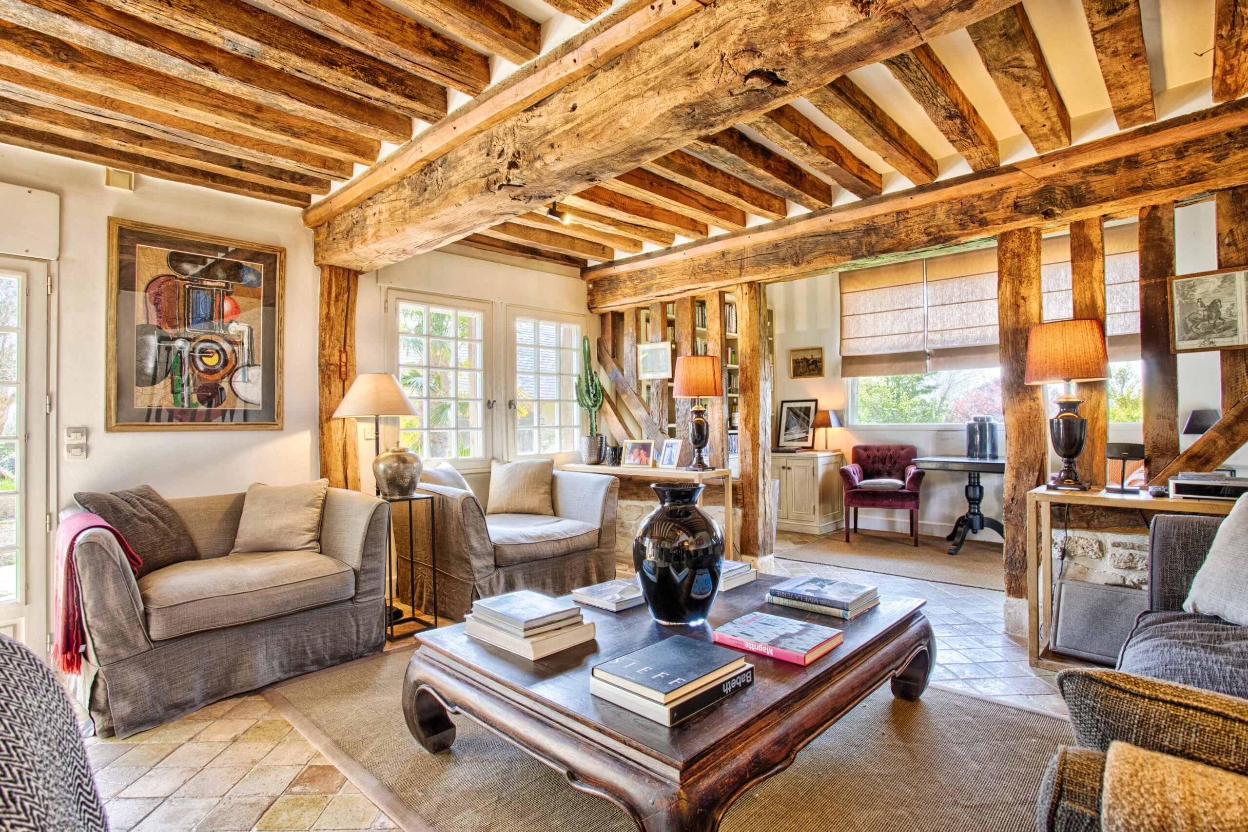 Salon chaleureux à la décoration authentique – Villa Constantin Coin salon décoré avec soin, poutres apparentes et lumière naturelle abondante dans la Villa Constantin