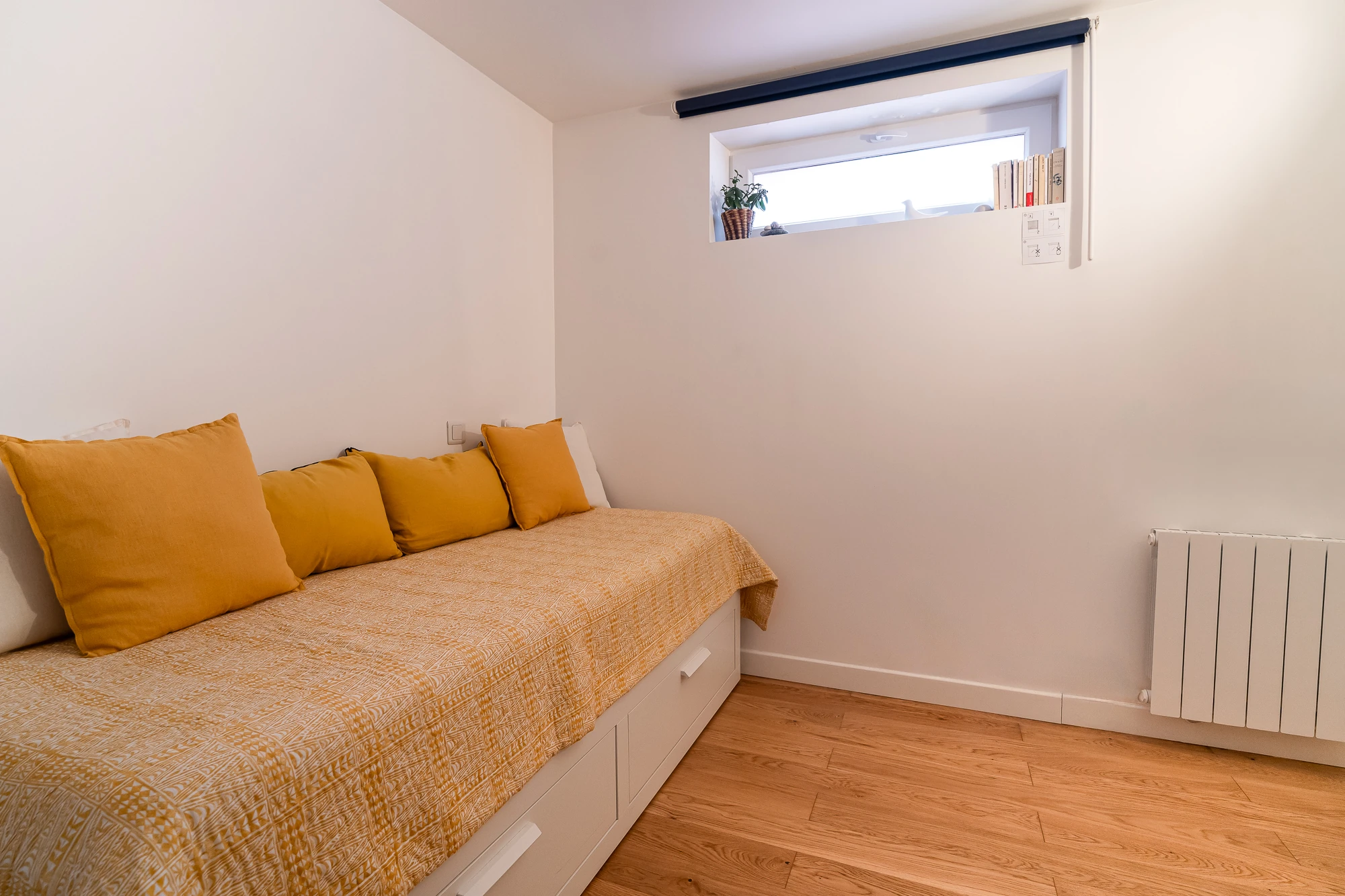Chambre cosy – La Maison Caracas Deauville Lit simple avec coussins jaunes dans une chambre épurée