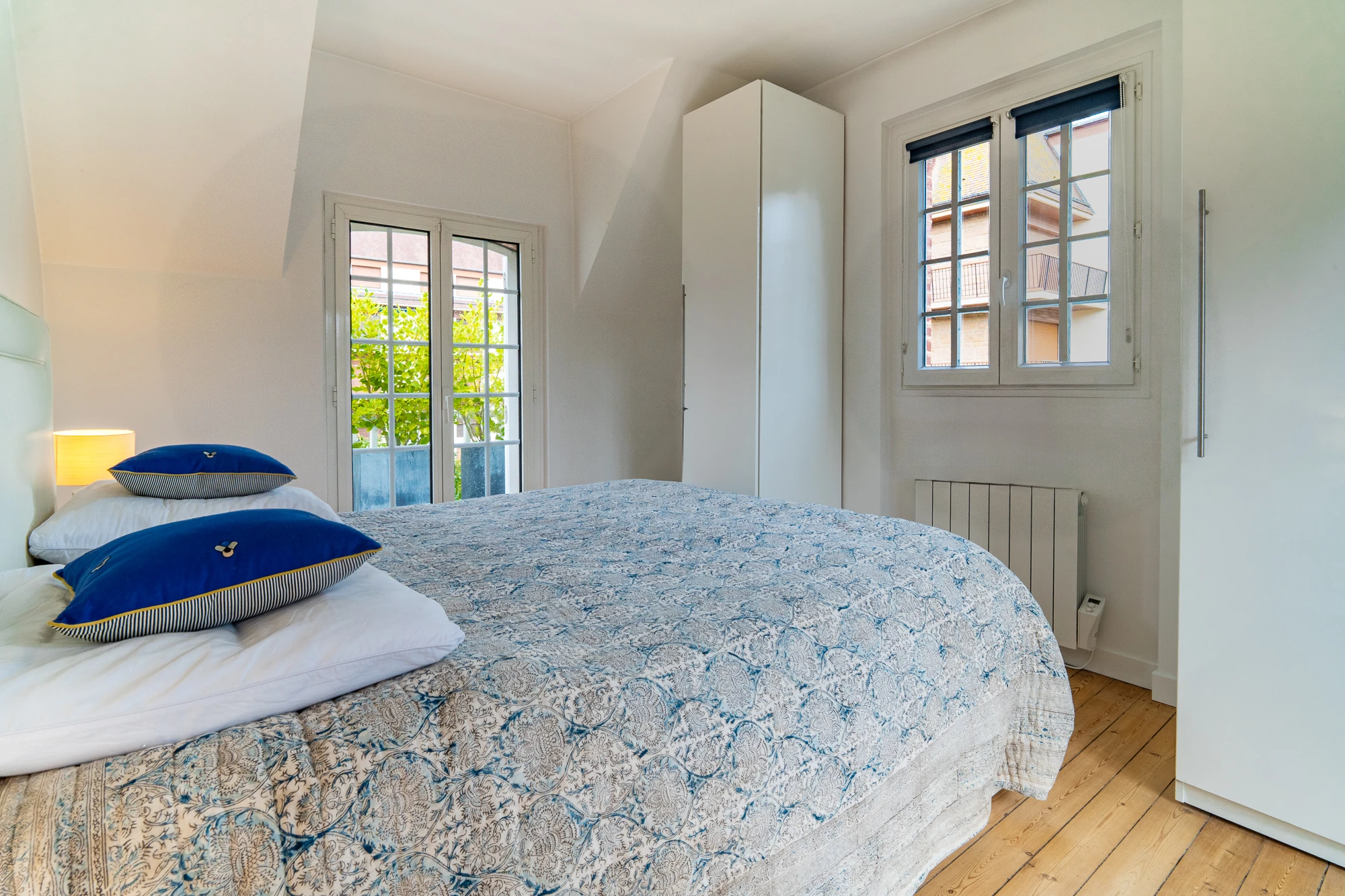 Chambre principale – La Maison Caracas Deauville Lit double avec coussins bleus et vue sur la terrasse