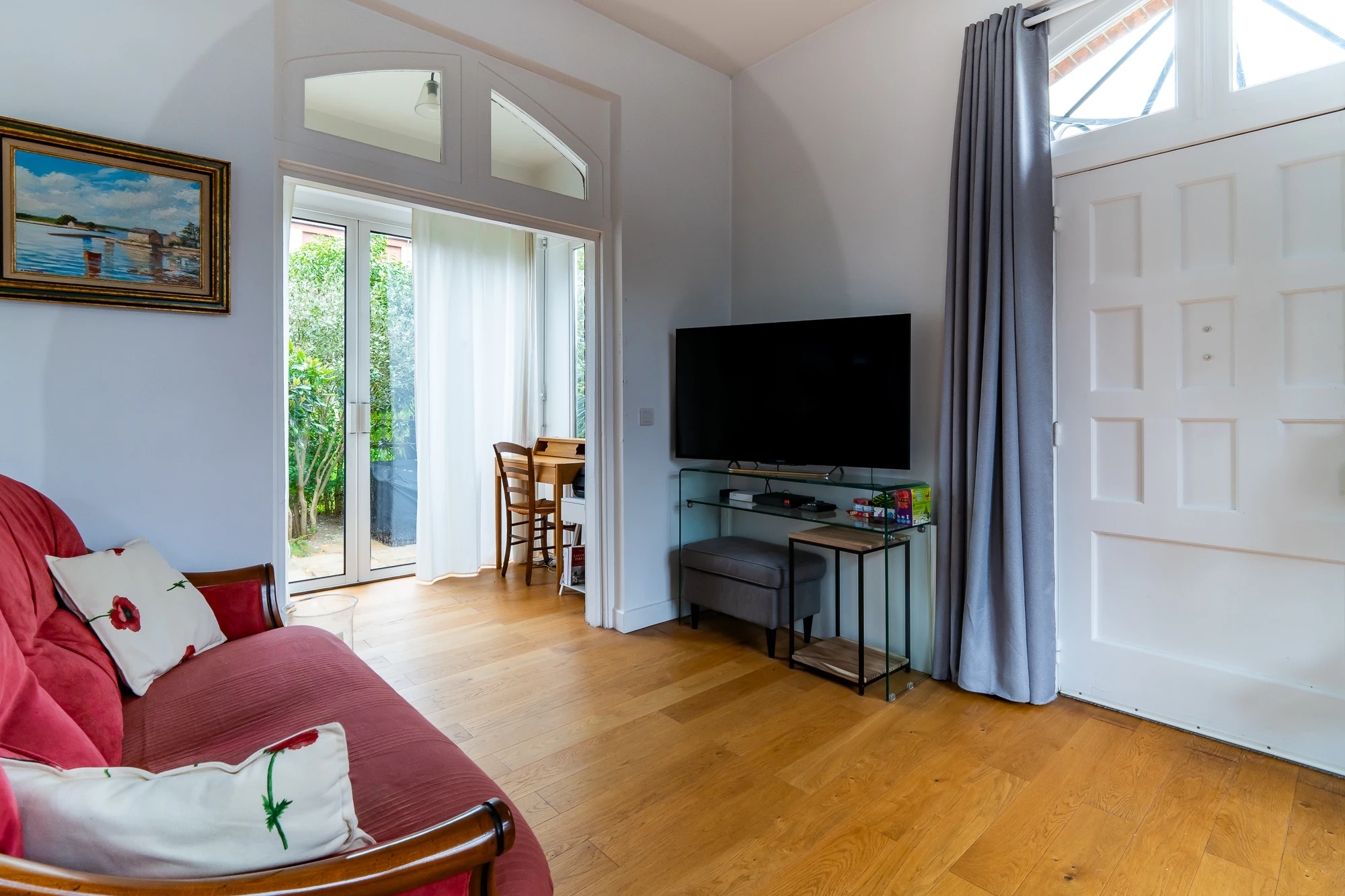 Coin TV – La Maison Caracas Deauville Télévision à écran plat face au canapé rouge dans le salon