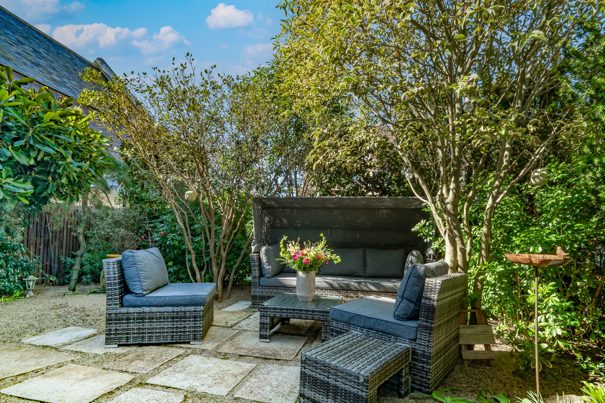 Espace détente extérieur – La Maison Caracas Deauville Salon de jardin ombragé avec fauteuils et canapé en rotin
