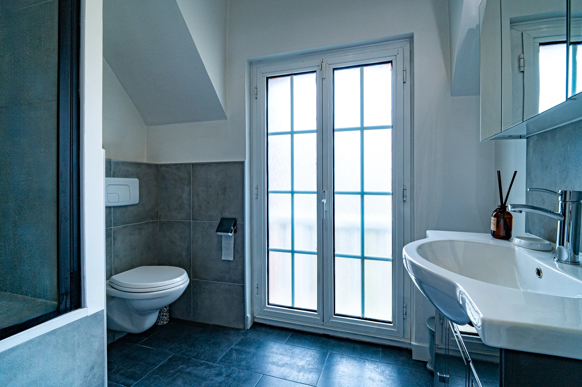 Salle de bain – La Maison Caracas Deauville Salle de bain avec toilettes suspendues, lavabo et grande fenêtre