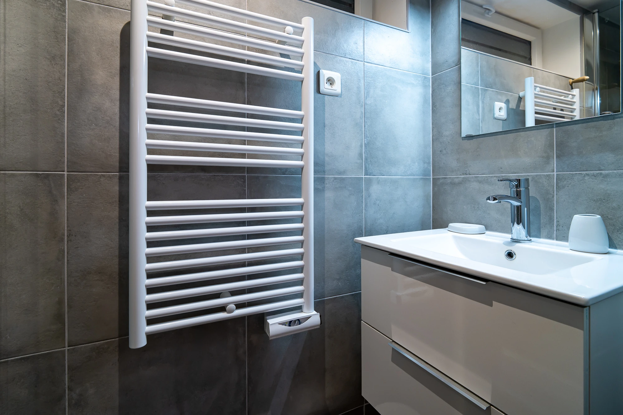 Salle de bain – Maison Caracas Deauville Salle de bain moderne avec carrelage gris, meuble vasque blanc et sèche-serviettes