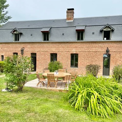 Maison traditionnelle en briques avec toit en ardoise, terrasse extérieure aménagée et jardin verdoyant en location près de Deauville