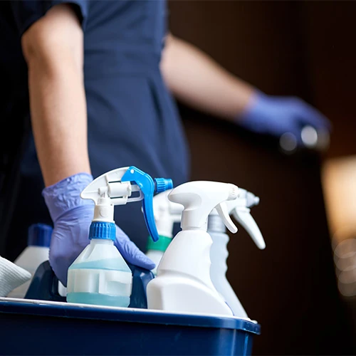 Employée de maison équipée de produits d’entretien, représentant le service de nettoyage professionnel inclus dans les prestations de conciergerie