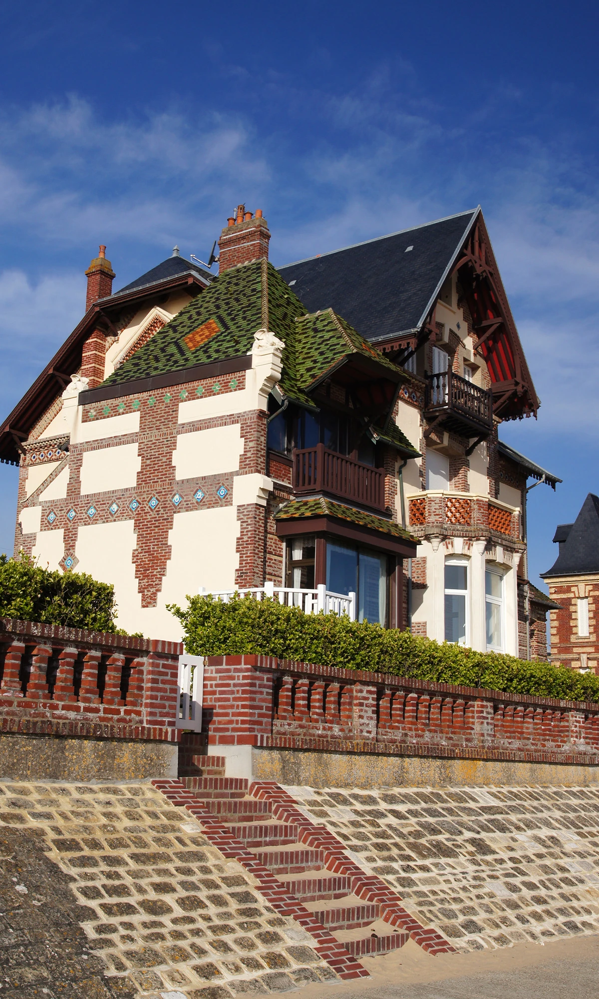 Maison en briques à colombages avec toiture en tuiles vernissées, située en front de mer à Deauville, illustrant un bien de prestige géré par la conciergerie