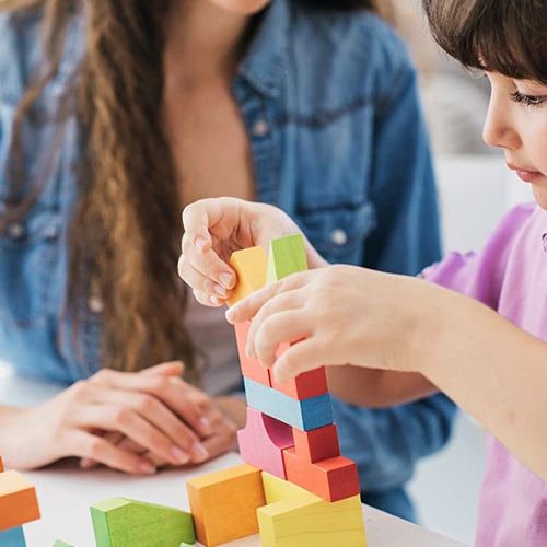 Enfant jouant avec des blocs colorés sous la surveillance d’une baby-sitter – prestation de garde d’enfants proposée par la conciergerie privée à Deauville
