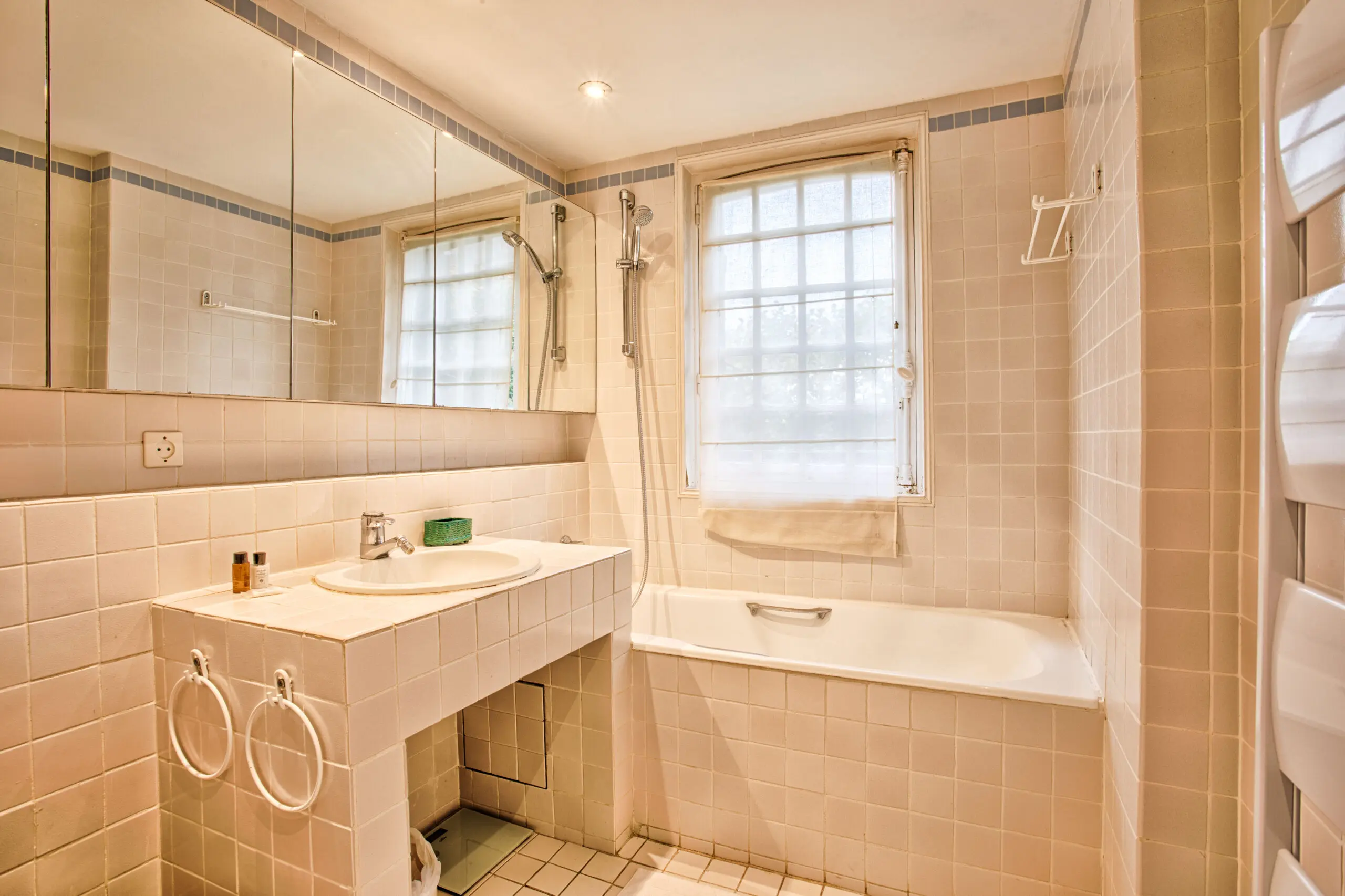 Salle de bain élégante avec baignoire, vasque encastrée et carrelage blanc