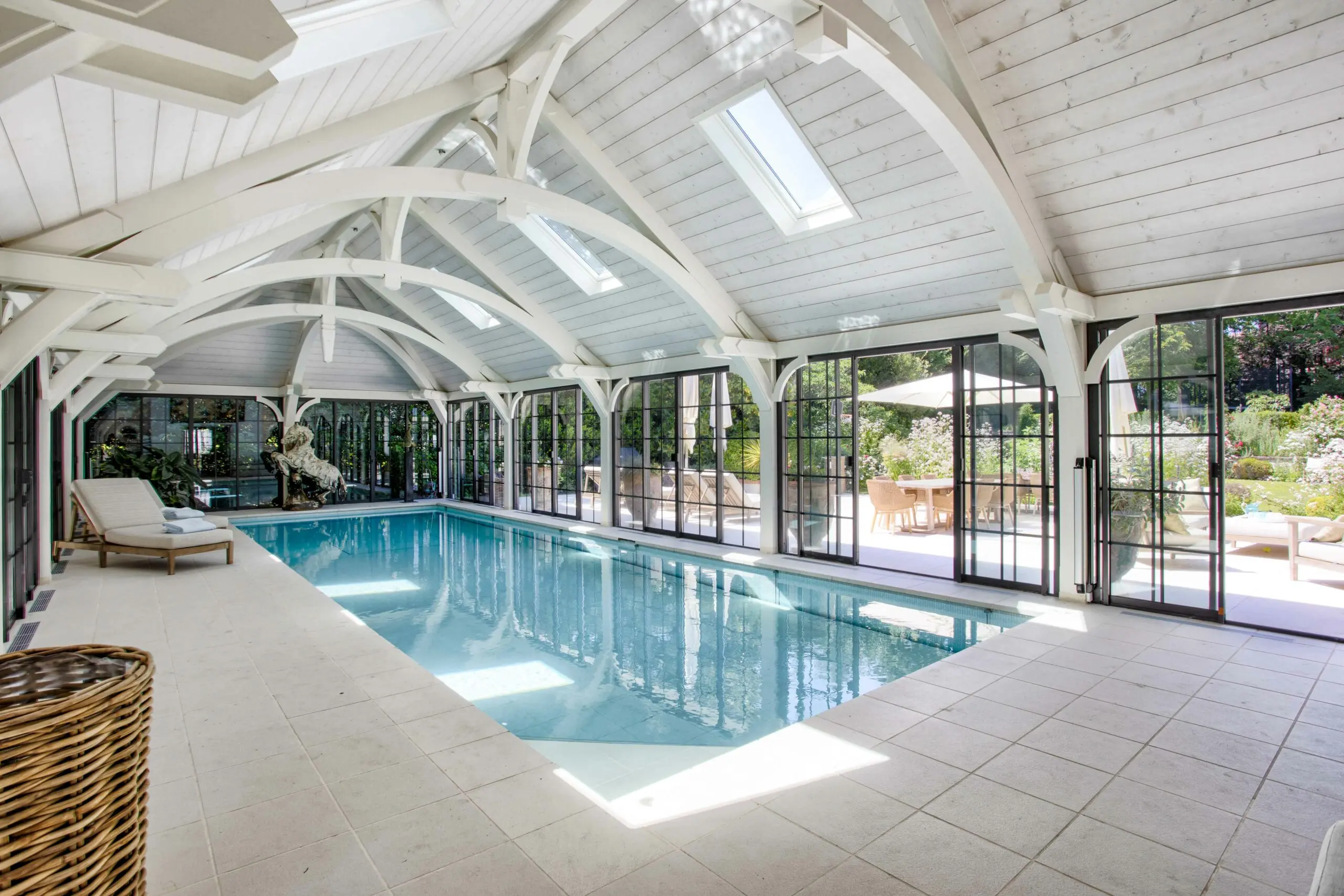 Piscine intérieure Piscine intérieure de luxe sous charpente en bois blanc dans une propriété d'exception gérée par conciergerie à Deauville