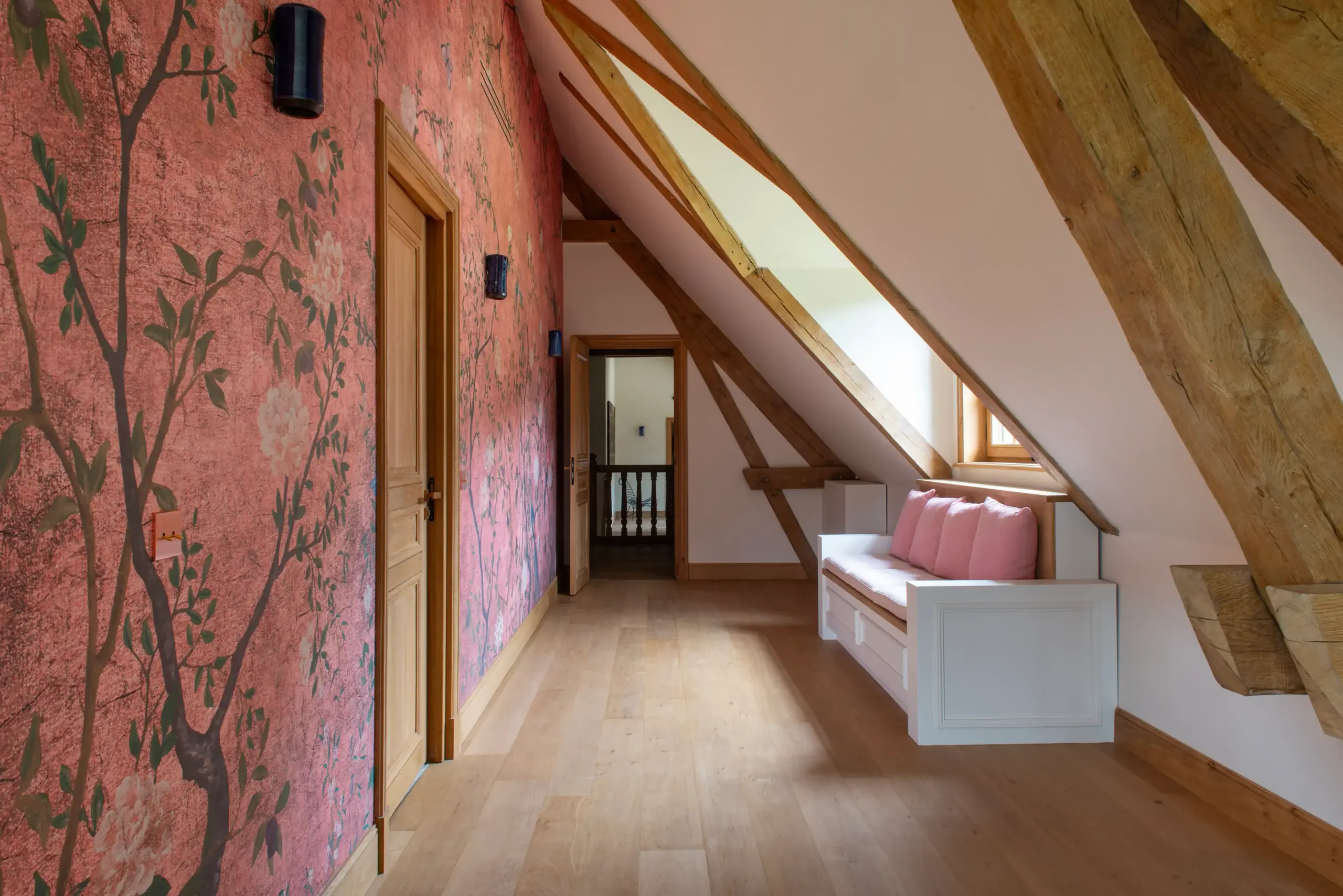 Couloir mansardé Couloir mansardé avec papier peint chinoiserie et charpente apparente dans une demeure de prestige gérée par conciergerie de luxe en Normandie