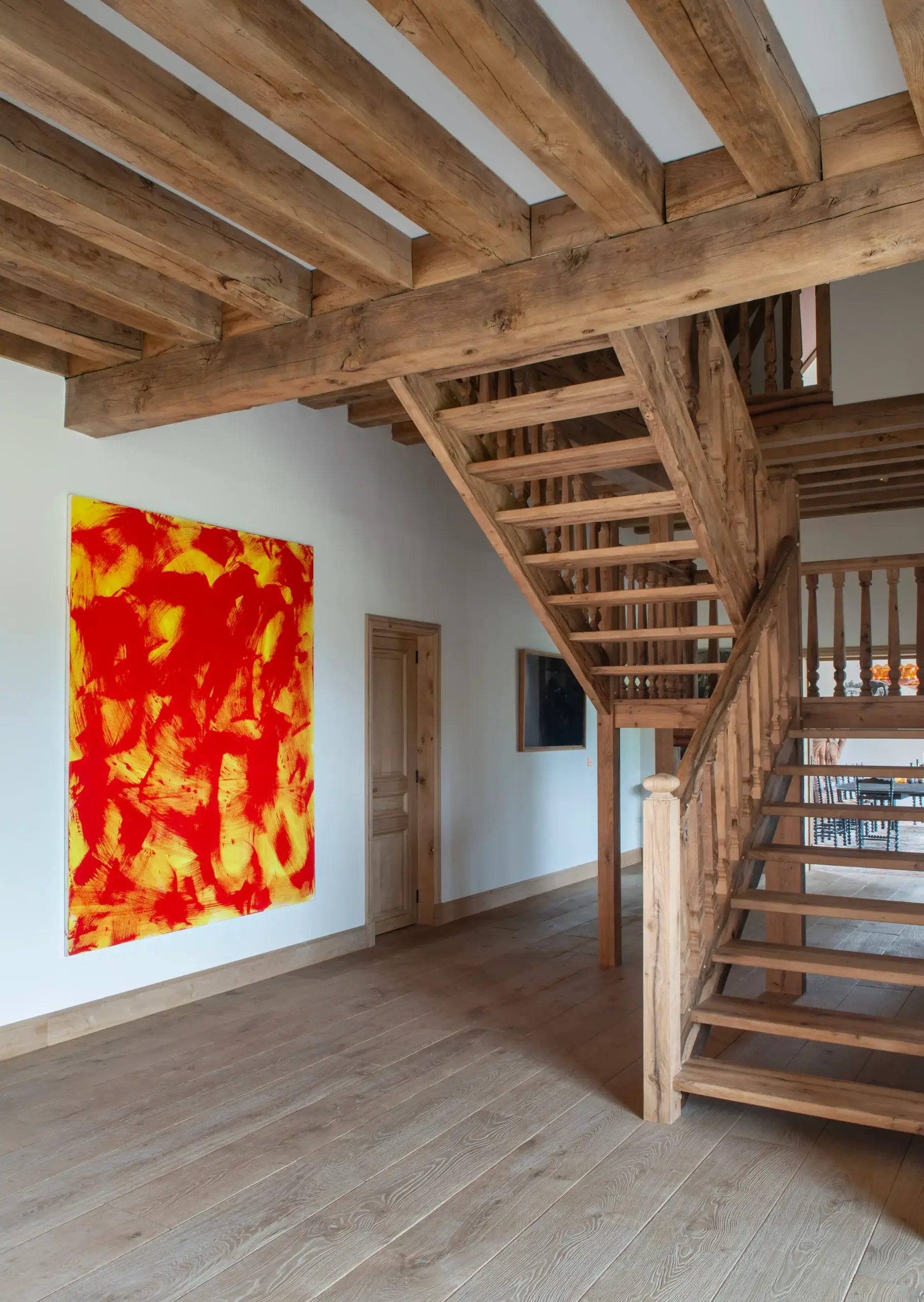 Escalier principal Hall d'entrée de prestige avec charpente apparente et grande peinture contemporaine dans une propriété d'exception accessible via conciergerie privée en Normandie