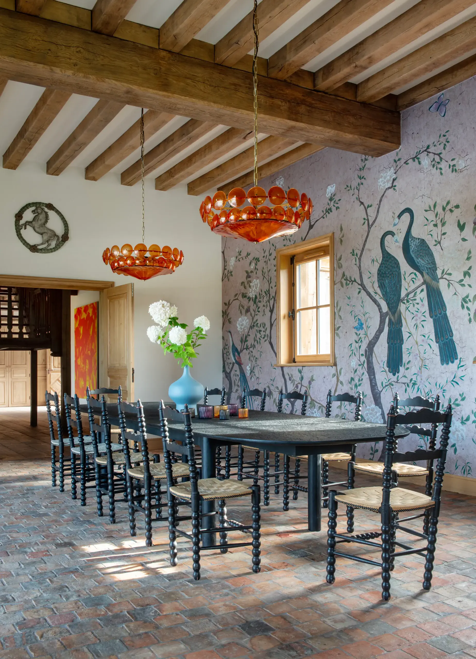 Table salle à manger Salle à manger de prestige avec fresque chinoiserie et lustres en verre soufflé orange dans une demeure normande gérée par conciergerie de luxe